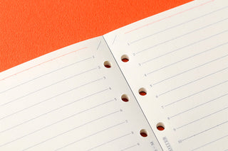 Close-up of 6mm ruled memo pad refill pages with punched holes along the fold