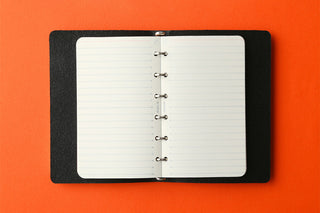 Open 6mm ruled memo pad refill inside a black cover, punched pages visible