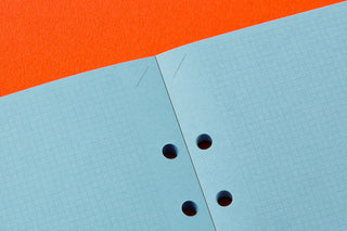 Close-up of blue 2mm grid paper with binder holes for memo pad refill
