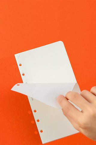 Plain memo pad sheets with punched holes, being inserted by hand