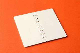 Open memo pad with plain pages and rows of punched holes