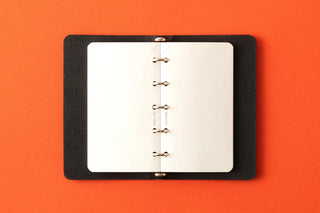 Memo pad refill insert in black holder, showing ring holes on white sheets