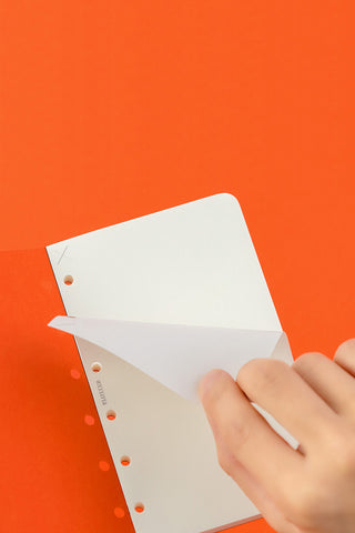 Mini memo pad refill sheets being inserted; punched holes on orange cover