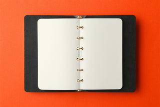 Open mini memo pad showing white pages and ring-style metal binder at center