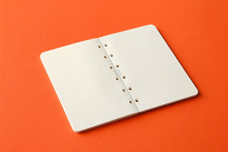 Closed mini memo pad with punched holes along the spine and white cover pages