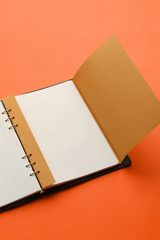 Open A5 planner angled view with black cover, white pages, and tan kraft insert