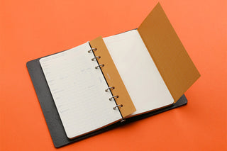 Open planner binder with white pages, tan panel, and dark cover base