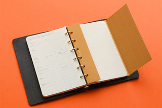Mini ring binder planner open with weekly grid pages and textured orange insert