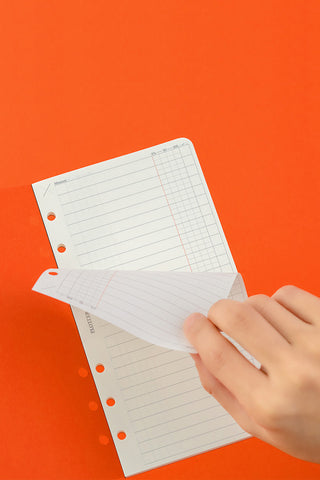 White grid memo pages with punched holes, hand holding the refill sheets