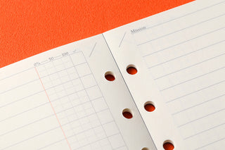 White grid checklist page close-up with punched holes and faint graph lines