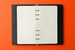 Open refill memo pad with white grid pages and metal rings on the center spine