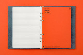 Open A5 6-ring leather binder showing ruled notebook pages and metal ring mechanism
