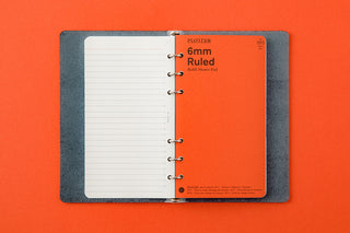 Open six-ring binder with 6mm ruled pages and metal rings on gray leather