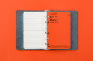 Blue-gray 6-ring leather mini binder open with ruled paper and metal rings