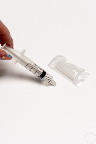 Clear plastic syringe with measurement markings and extra cleaning cartridge in pouch