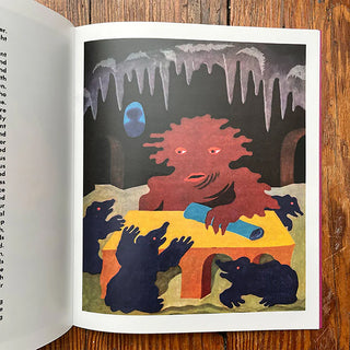 Open storybook page with a red monster in a dark cave and black animals