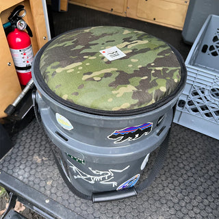 Circular woodland camo Cordura seat pad on gray container with black trim