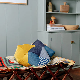 Indigo patchwork cushion on sofa with checkered front and striped side panels