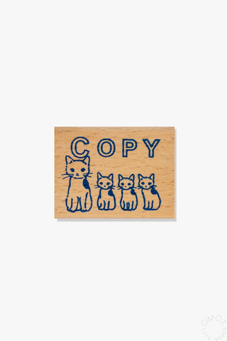 Small wooden stamp with blue "COPY" text and four cat figures