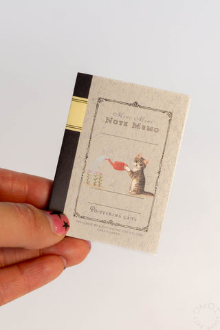 Mini note memo card held in hand, with pottering cat artwork and lined section
