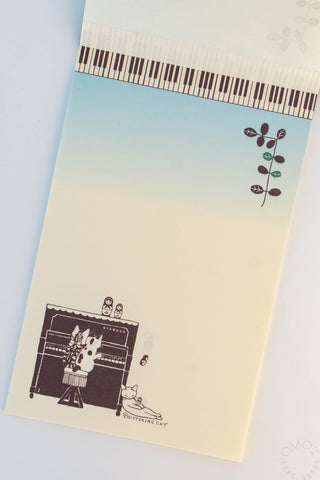 Cat piano letter pad with top piano keys, branch graphic, and small cats at bottom