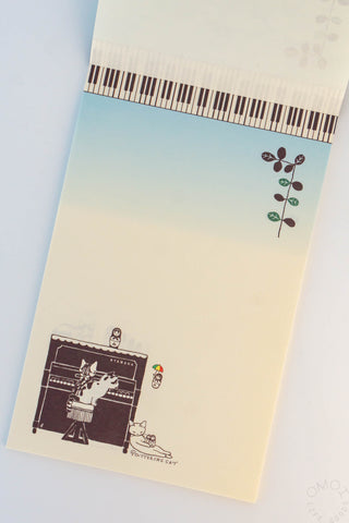 Cat and piano letter pad showing piano-key strip, branch motif, and cats by piano