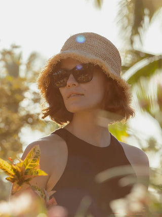 Tortoise-pattern sunglasses on woman wearing bucket hat, dark lenses
