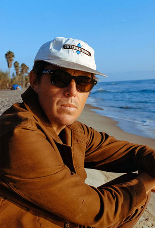 Teal sunglasses worn outdoors with dark brown lenses and a cap