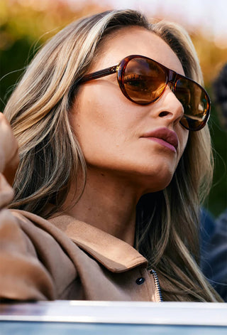 Amber tortoise sunglasses with tan lenses worn by a woman outdoors