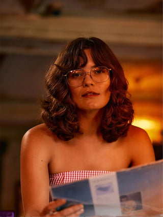 Woman with medium-length hair wearing silver sunglasses with brown tinted lenses.