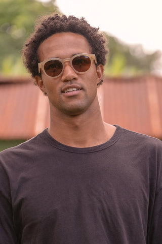 Round sunglasses on person with dark brown lenses and light frame