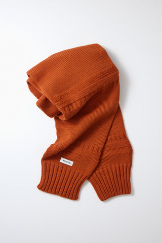 Orange knit sweater sleeve muffler, folded hood and ribbed cuff knit.