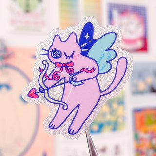 Radhia Rahman Cupid Kuni sticker, glitter outline of a blue witch cat holding a heart