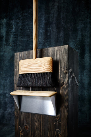 Wood-handled dust pan with attached brush and dark bristles