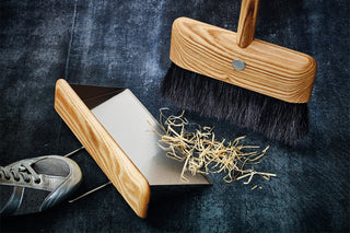 Wood dust pan with stiff brush sweeping debris into the scoop
