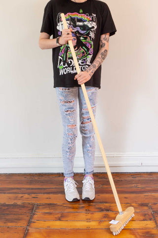 Rubber lint broom with wooden handle, held upright