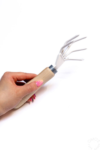 Redecker hand cultivator held in hand, light wood handle with metal fork tines