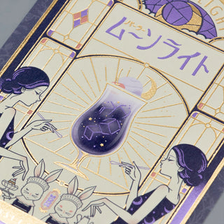 Foil postcard close-up with purple moon panel, gold linework, and purple lettering