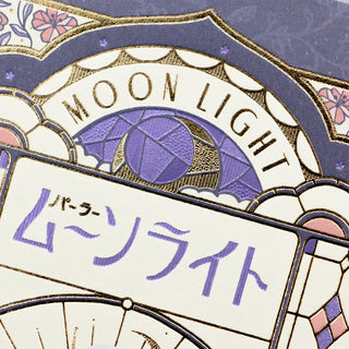 Foil postcard close-up with arched MOON LIGHT text, purple umbrella moon, and gold trim