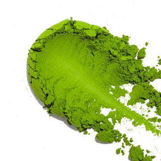 Green matcha powder mound with scattered powder and scoop-like shape
