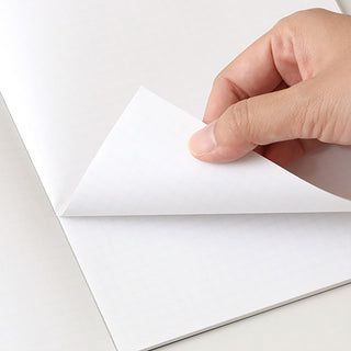 Pocket grid notebook pages, white paper being lifted and folded by a hand