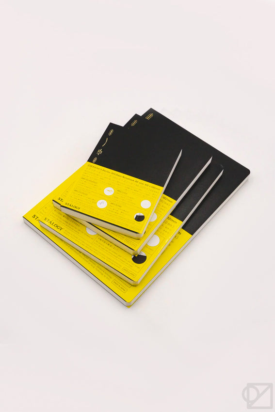 STÁLOGY 018 grid editor's notebooks stacked, black and yellow covers