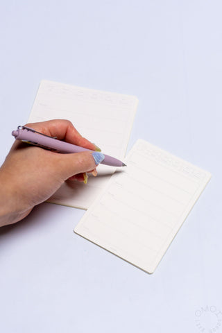 Hand writing on beige weekly calendar sticker sheets with horizontal schedule lines
