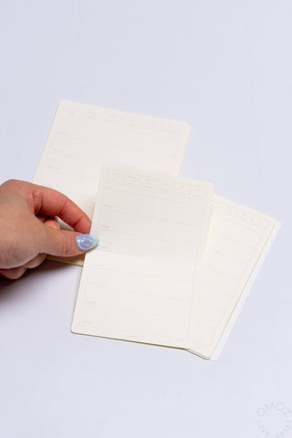 Hand placing beige weekly calendar sticker sheets over a planner grid