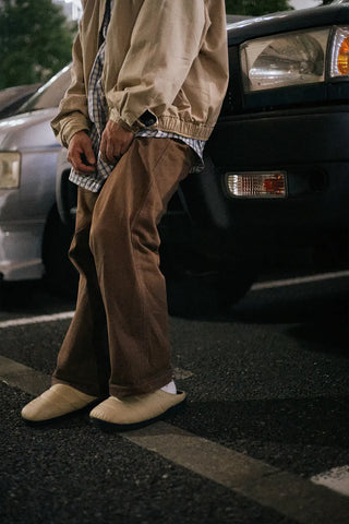 Beige quilted slip-on slippers with dark sole worn outdoors