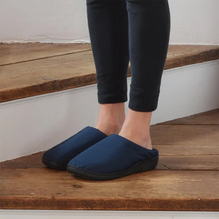 Navy slip-on outdoor slippers worn by a person standing on wood