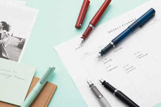 Translucent navy TUZU Adjust fountain pen on planner sheets with cap and nib visible