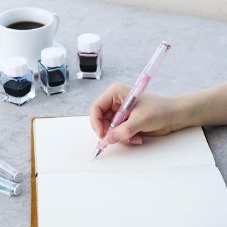 Hand writing with pink glassy fountain pen on white paper