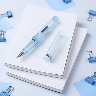 Light blue glassy fountain pen on open notebook with matching pen cap