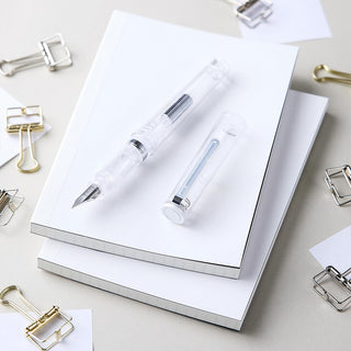 Glassy fountain pen with transparent barrel and nib, resting on papers